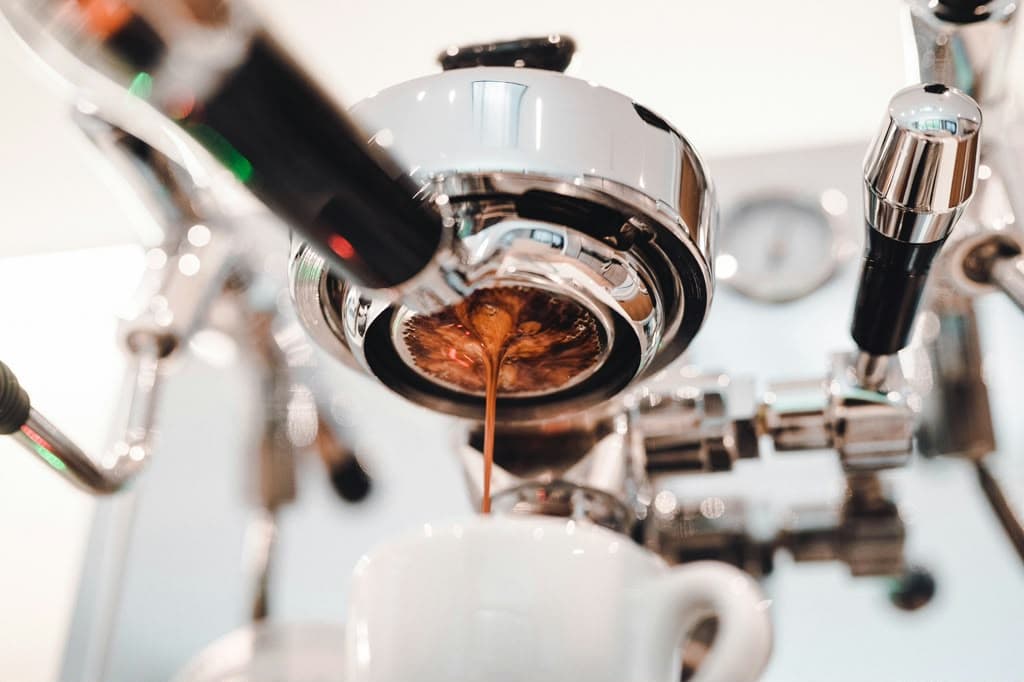 Espresso pouring from the machine into a white cup