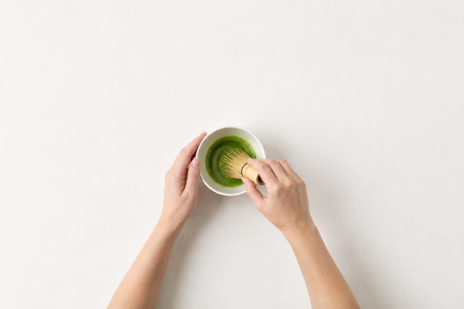 Hands whisking matcha in a bowl